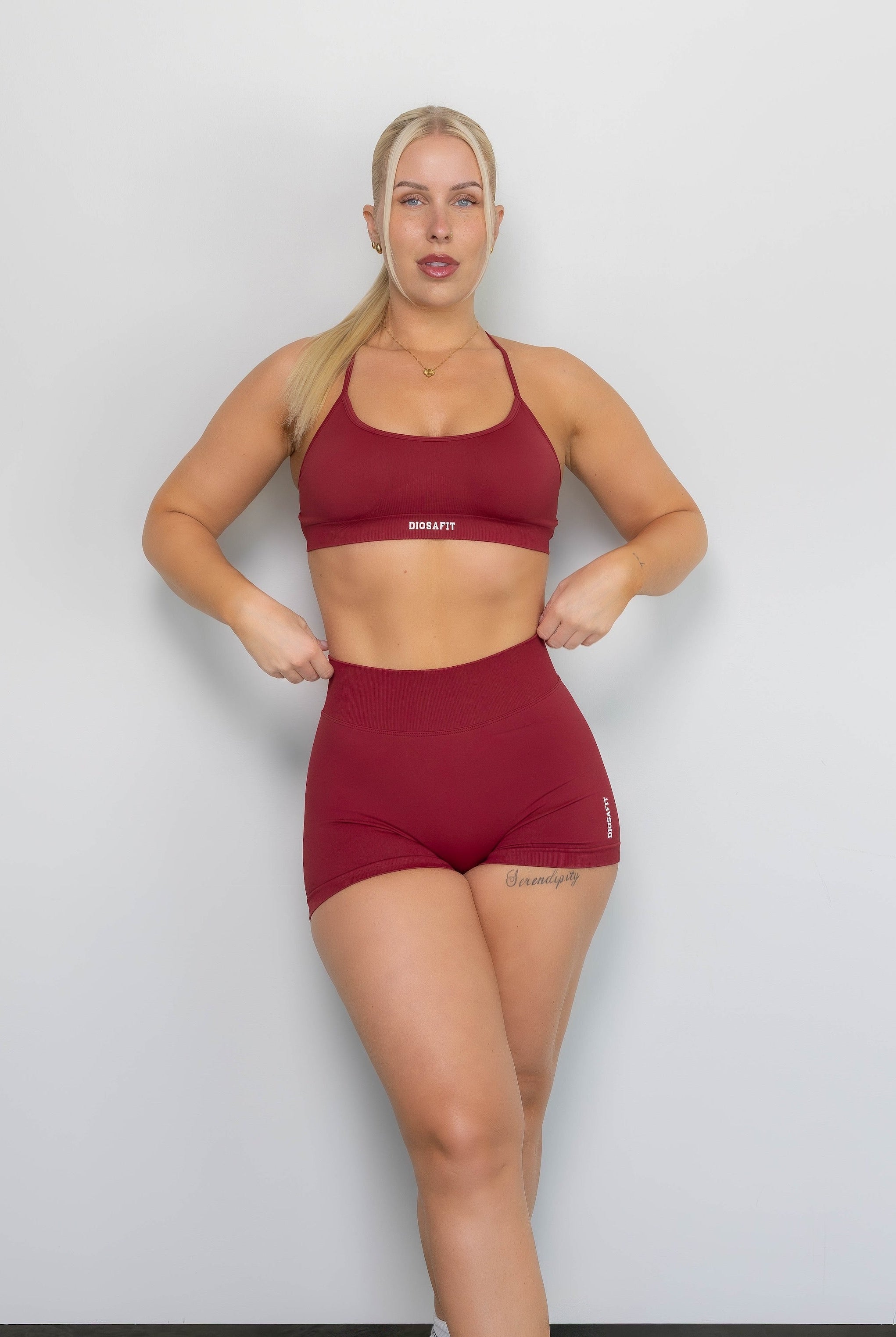 Woman wearing a red sports bra and shorts set against a white background