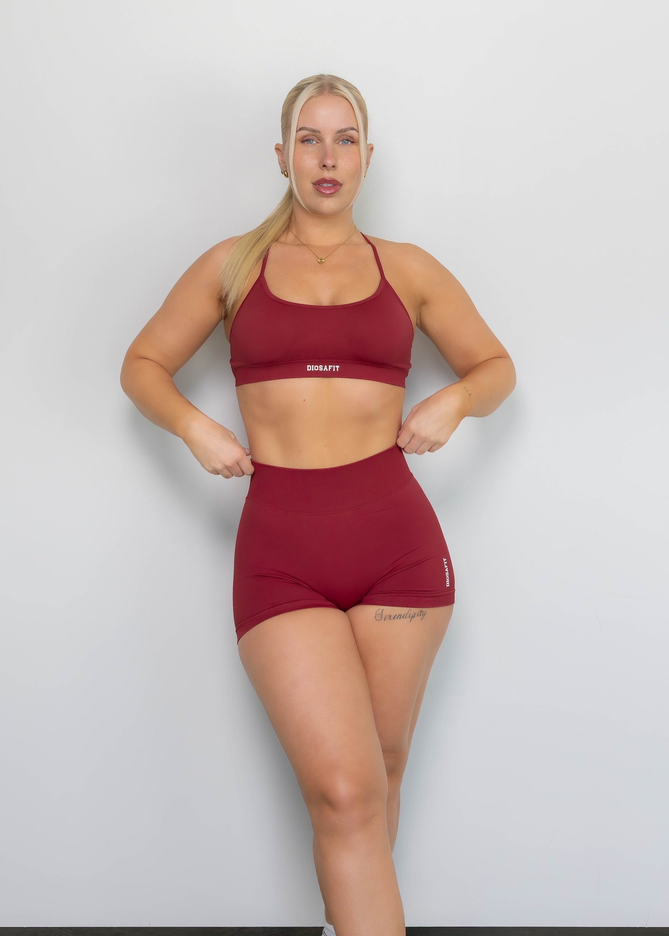 Woman wearing a red sports bra and shorts set against a white background