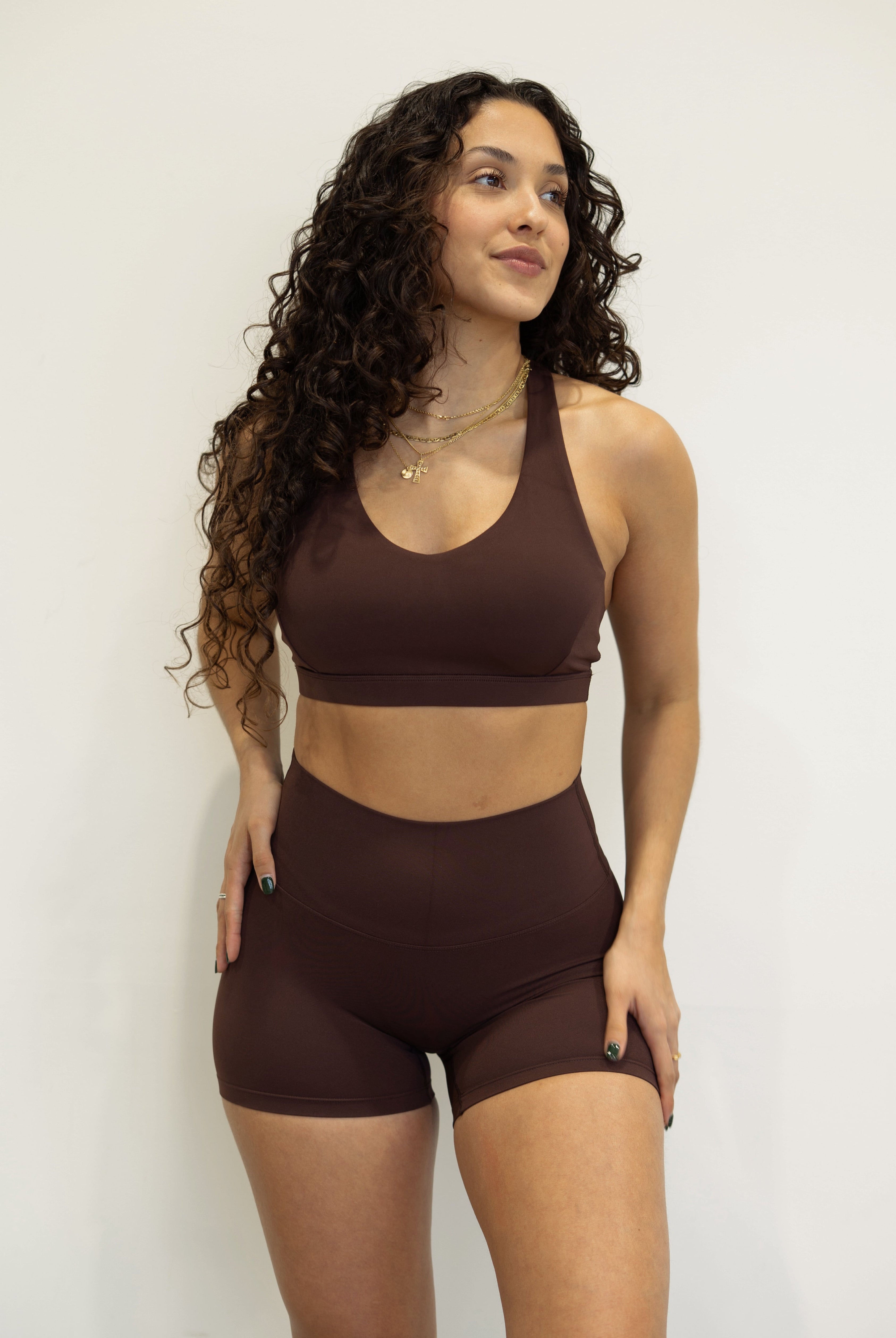 Woman wearing a brown sports bra and shorts set against a plain background